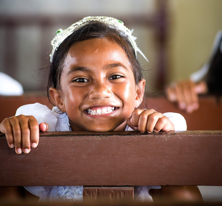 A young girl is dressed up for church in Tonga.  