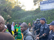 Students under the umbrella of the Wits SRC face a cordon of security officers at Wits University during a demonstration.