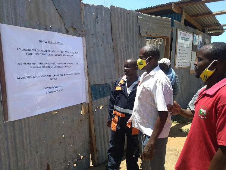 Workers read a discouraging notice at the gate of the site in Nyali on Friday.