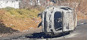 A burnt-out vehicle is overturned in the middle of the road as protests intensified in Johannesburg on Sunday.