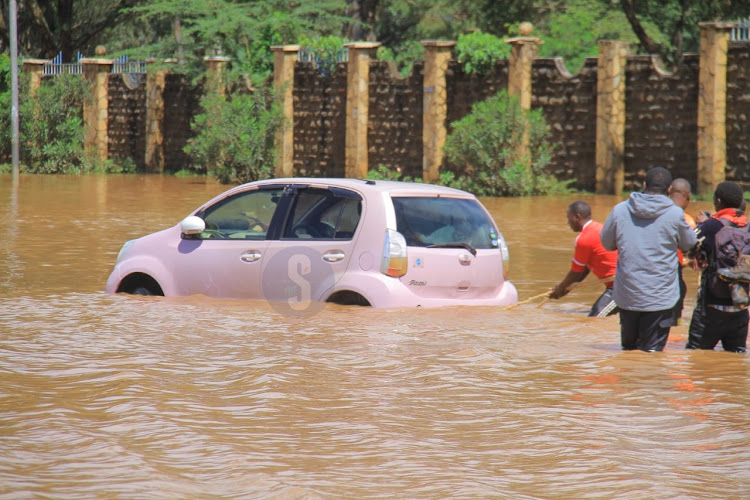 Rescuers try to remove a car that has been stuck in the rain water at Kenyatta University area on Wednesday, May 1, 2024.