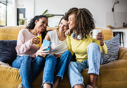 Three women sitting on a couch and laughing
