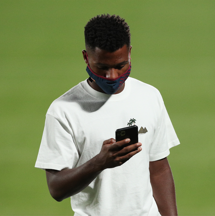 Barcelona's Ansu Fati checking on his phone while wearing a protective face mask