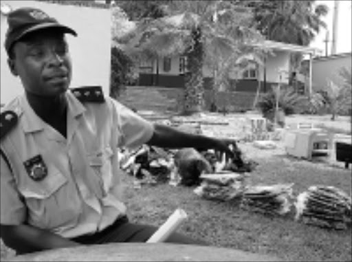 JUST THE THING: Lebombo police commander Senior Superintendent Mike Mhlanga points out the clothes with expensive brand labels. The clothes were confiscated from Mozambican criminals who were on their way to sell them in South Africa. The police also confiscated illegal cigarettes as well as bottles of Tentacao whiskey, a potent drink that is not allowed in this country. Pic. Riot Hlatshwayo. © Sowetan.