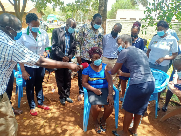 A resident of Bondo town receives the Covid-19 jab as leaders led by area sub county commissioner Richard Karani look on.