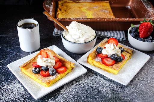 Two slices of Pannaukkau (Finnish or Swedish Pancake) with fruit and whipped cream.