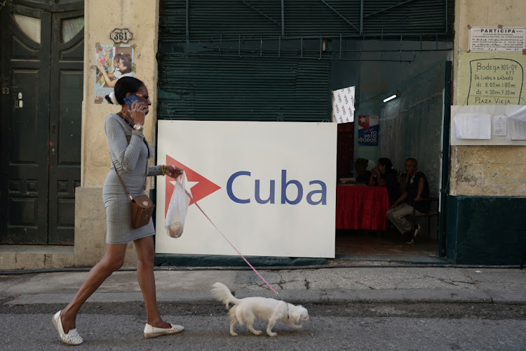 A woman walks a dog past a polling station during the legislative elections in Havana, Cuba, March 26 2023. Picture: ALEXANDRE MENEGHINI/REUTERS