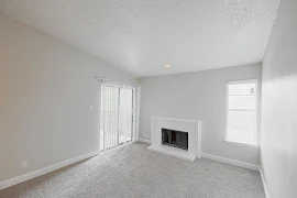 Living room with carpet, light neutral walls, a window, and a white brick fireplace