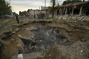 People stand near a crater left by a Russian missile strike, as Russia's attack on Ukraine continues, in Dnipro, Ukraine July 16, 2022.  