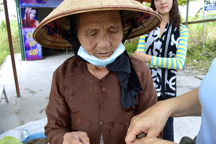 A woman merchant wears a typical hat to shield herself from the sun.