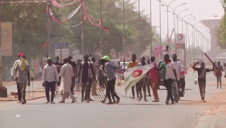 Protesters wield batons and hold a picture of opposition presidential candidate Mahamane Ousmane along a road, a day after Ousmane rejected election results that gave his opponent Mohamed Bazoum a majority of the votes, in Niamey, Niger on February 24, 2021, in this still image taken from video.