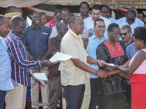 Mombasa Governor Hassan Joho, DP William Ruto, President Uhuru Kenyatta and Lands CS Jacob Kaimenyi issue a title deed to a resident of the Waitiki Farm in Shika Adabu Grounds, Likoni, on January 9.