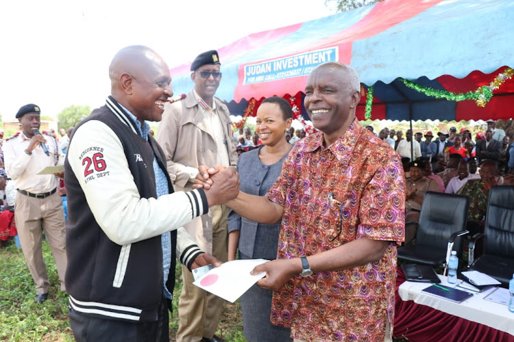 Makueni governor Kivutha Kibwana gives a title deed to a resident of Wayani village in Nzaui sub-county as Makueni County commissioner Maalim Mohammed and NLC commissioner Gertrude Nduku look on