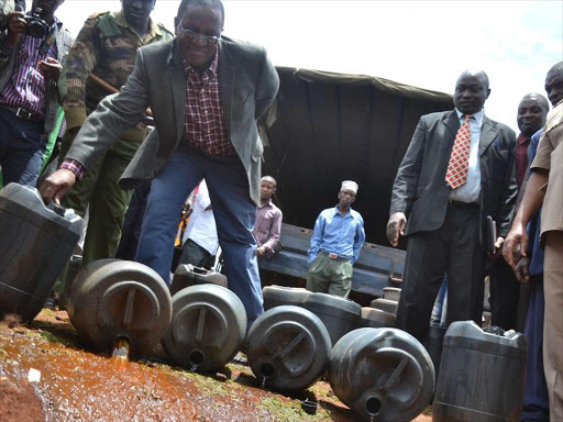 Interior PS Karanja Kibicho pouring some of the illicit brews impounded in Nyeri.Photo/File