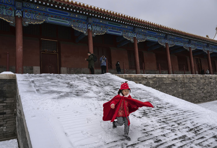 A child runs down a snow covered ramp in the Forbidden City a day after the first snowfall of the winter on December 12, 2023 in Beijing, China. Picture: KEVIN FRAYER