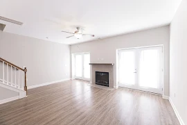 Living room with wood-inspired flooring, a ceiling fan, two separate patio doors, window, and tiled fireplace