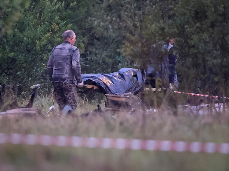 Emergency specialists carry a body bag near wreckage from the private jet linked to Wagner mercenary chief Yevgeny Prigozhin at the crash site in the Tver region, Russia, on August 24, 2023.