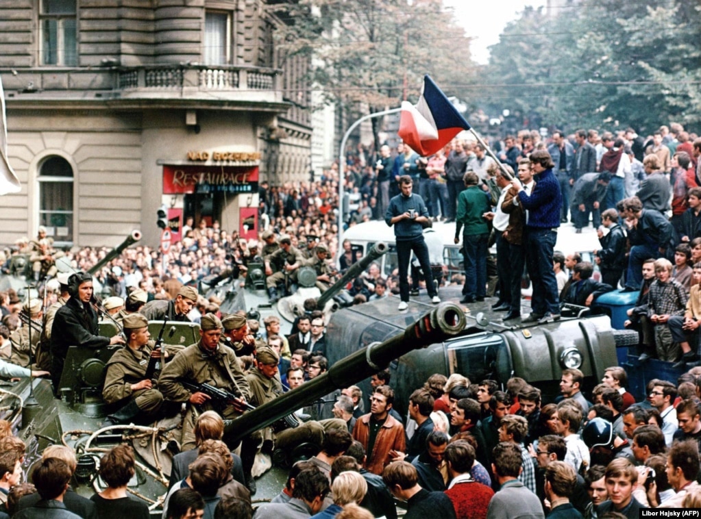 Czechoslovakia -- Czech youngsters holding a Czechoslovak flag stand atop an overturned truck as other Prague residents surround Soviet tanks in Prague on 21 August 1968