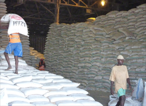 Workers arrange bags of wheat in a godown at the Port of Mombasa/
