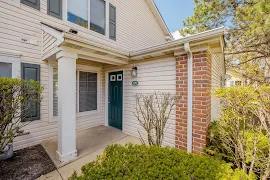 Exterior of apartment entry door with concrete patio, green door, and lighting sconce 