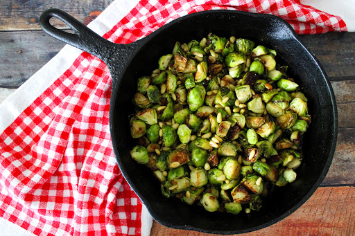 Sauteed Brussels Sprouts with Pinion Nuts in a cast iron skillet.