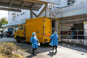 Workers wearing personal protective equipment (PPE) at the Fu Shan Public Mortuary in Hong Kong, China, on Friday, March 4, 2022. Hong Kong's mortuaries are so overwhelmed they're deploying mobile refrigeration units to store bodies, as scenes reminiscent of the early days of the pandemic play out amid the city's worst Covid-19 wave yet. 