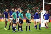 Referee Jaco Peyper and assistant referees, Nic Berry and Paul Williams look up at the big screen awaiting the decision from the TMO during the Rugby World Cup 2019 Quarter Final match between Wales and France at Oita Stadium on October 20, 2019 in Oita, Japan. 