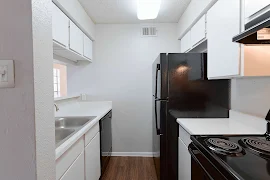 Kitchen with white cabinets, white countertops, black appliances, dark wood floors