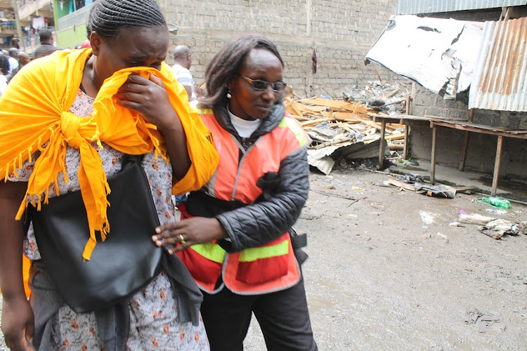 A bereaved woman is helped to a counselling desk by a KDF official following the Tassia building tragedy on Monday, December 9, 2019