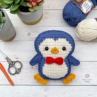 blue penguin on wooen background with yarn and hook