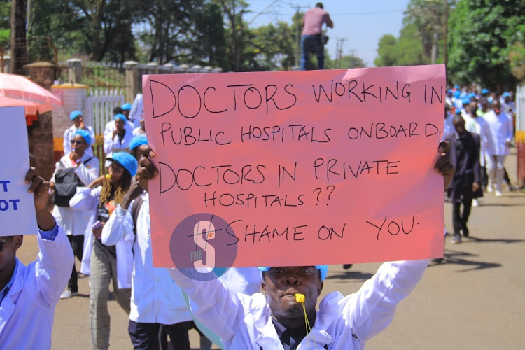 A doctor holds a placard as he also blows a whistle during protests along Ngong road over the posting of interns on March 22, 2024.