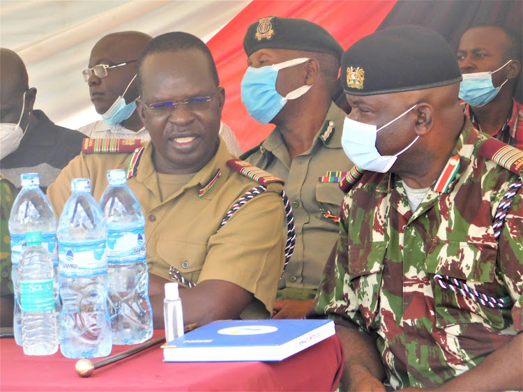 Coast Regional Commissioner John Elungata consults with Kilifi County Commissioner Kutswa Olaka during a public rally at Kasikini village, Magarini constituency.