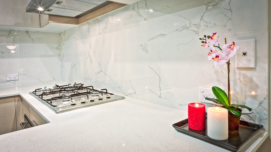 Two Light Red and White Pillar Candles Beside Pink Orchid Flowers in Kitchen