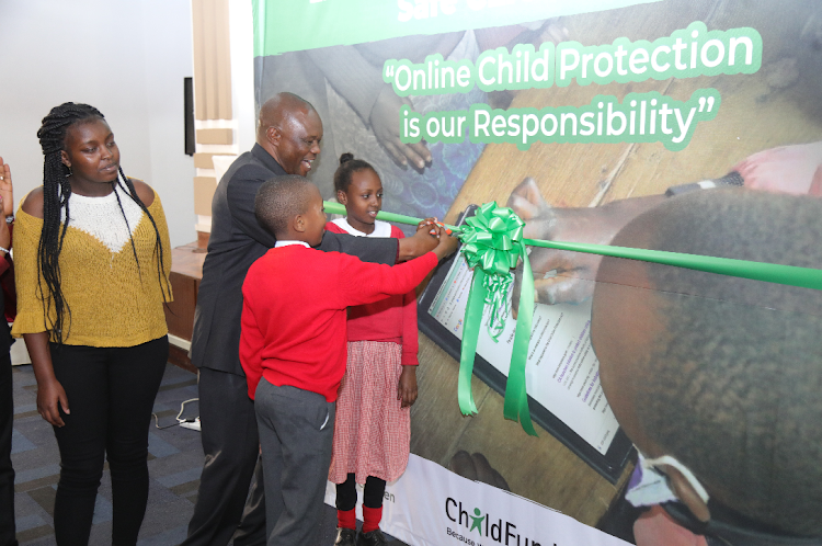 Charles Ondongo, the director of Department of Children's Services in the State department for Social Protection, leads pupils of Mukuru Primary School, Nairobi, in the official launch of the Safe Community Linkages for Internet Child Safety (Safe CLICS) programme.