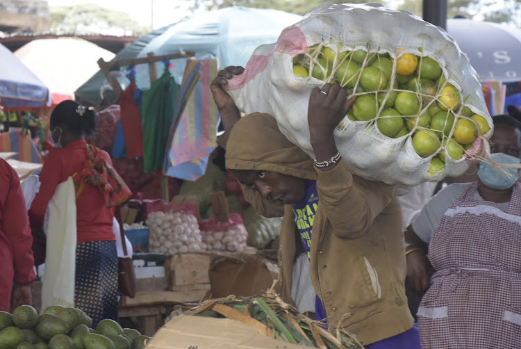 A trader carries a bag of oranges at Ruiru market on Tuesday.