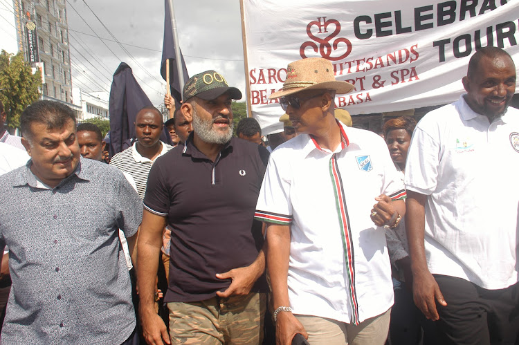 Mombasa Governor Abdulswamad Nassir and veteran hotelier Mohammed Hersi flanked by hundreds of Mombasa residents during a walk to commemorate the World Tourism Day event in Mombasa on Wednesday.