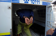 A man gets inside a police van after his appearance at the Court.