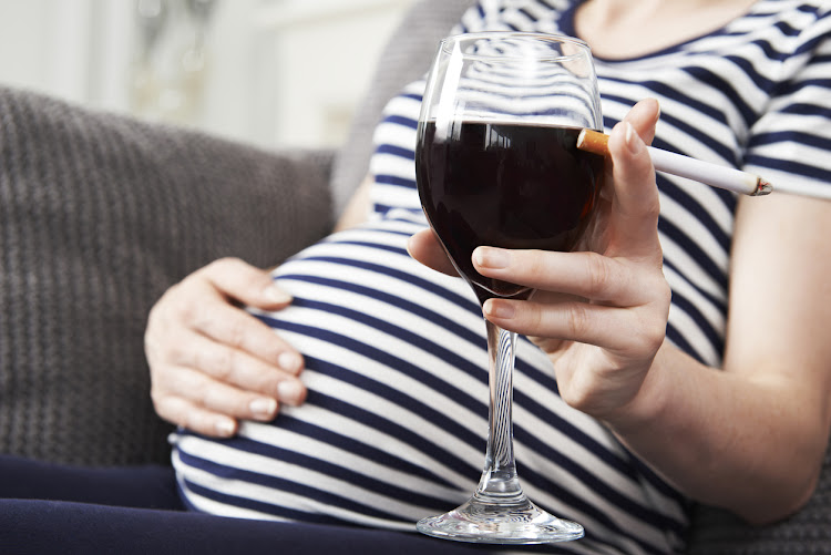 A pregnant woman drinking and smoking. File photo.