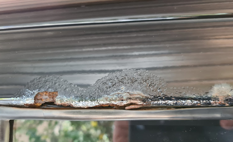 A detail of rust around a window weather seal.