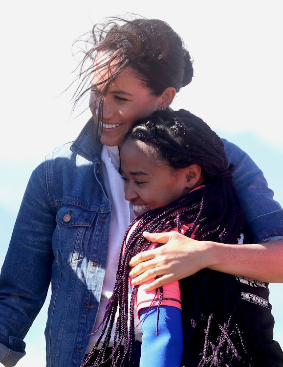 Meghan, Duchess of Sussex, hugs a surf mentor as she visits the NGO Waves For Change at Monwabisi Beach, on September 24 2019 in Cape Town.