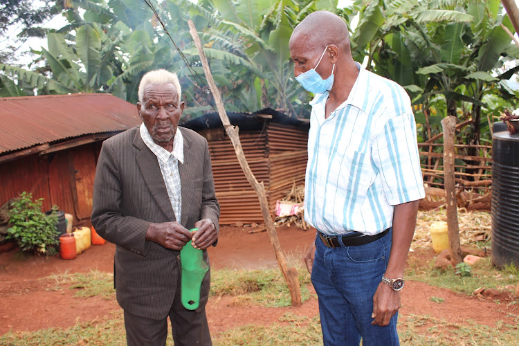 Thomas Mwaga with a neighbour in his home in Ichagaki village, Maragua.