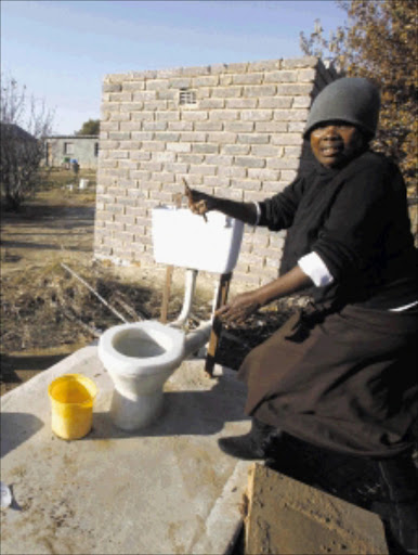 Mantsho Ndezi points to the toilet belonging to her neighbour, which is still not enclosed Pictures: SYDNEY SESHIBEDI