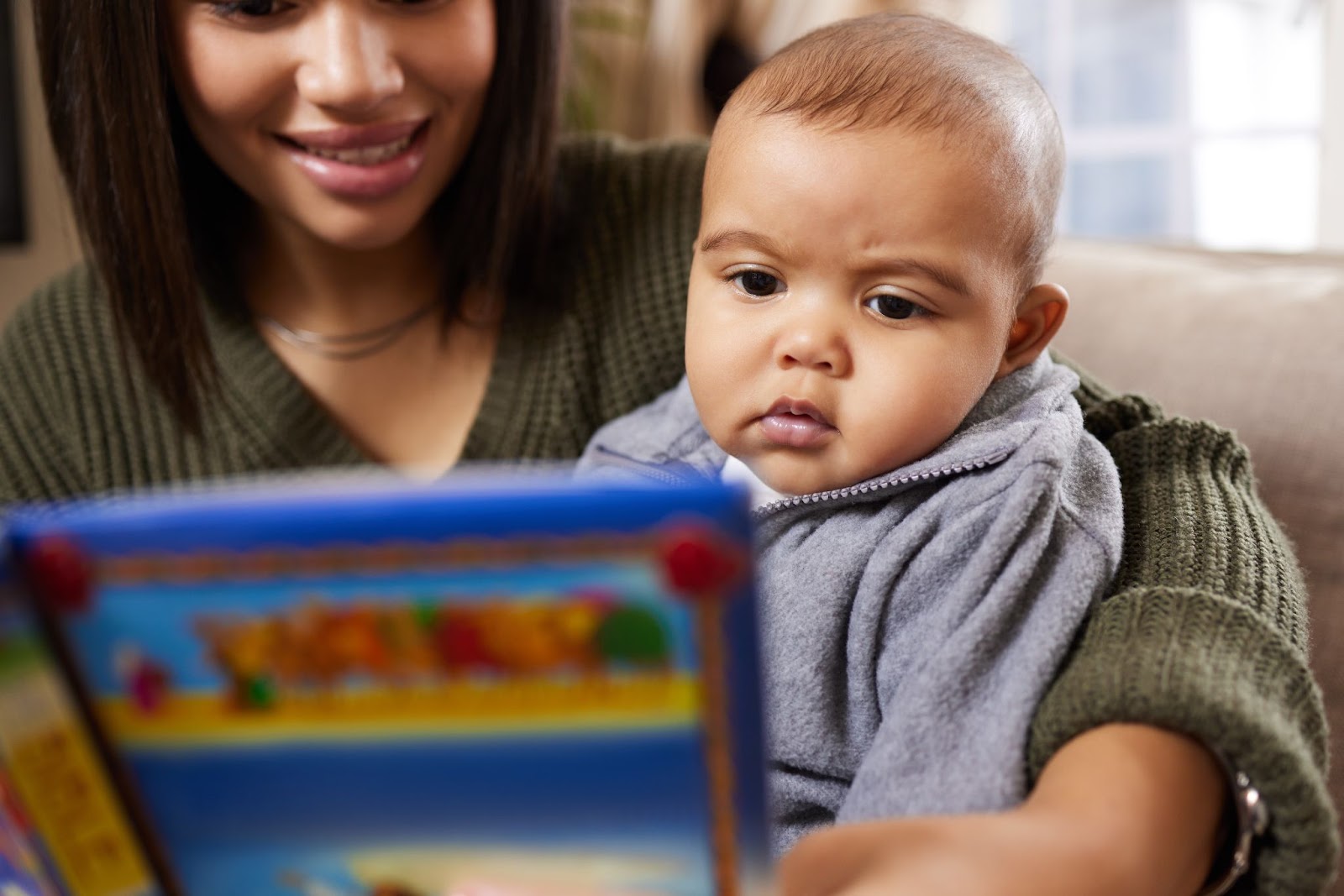 A mom and a baby looking at a Board Book together. 