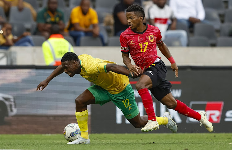 Bafana Bafana's Bongokuhle Hlongwane goes down under the challenge of Vladimir Felix of Angola in the international friendly at Mbombela Stadium on November 20 2022.