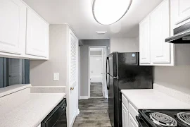 Kitchen with wood-inspired flooring, black appliances, and white cabinets