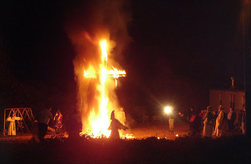 A burning cross. Cross burning is generally associated with acts of racism undertaken by members of the Ku Klux Clan.