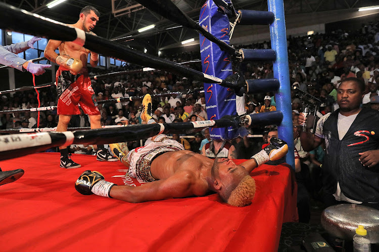 Tajikistani Shavkat Rakhimov stands over Azinga Fuzile in the eighth round in a dramatic end to their IBF junior lightweight title eliminator bout at the Orient Theatre in East London on Sunday.