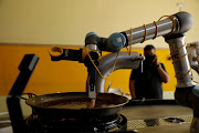 A robot created by Spanish companies br5 and Mimcook drops shrimp into a paella during a demonstration at a warehouse in San Fernando de Henares, outside Madrid, Spain, May 20, 2021.