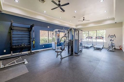 Fitness center with cardio machines, weight equipment, and several windows