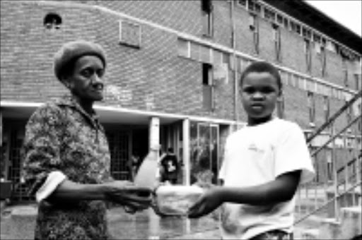 SUPPER TIME: Jeanetta Mashinini hands over food to her nephew, Bongani Sabisa, at the gate of Helen Joseph women's hostel in Alexandra. Boy children aged seven and older are not allowed to stay with thier mothers at the hostel. 25/01/2009. Pic. Mohau Mofokeng. © Sowetan.